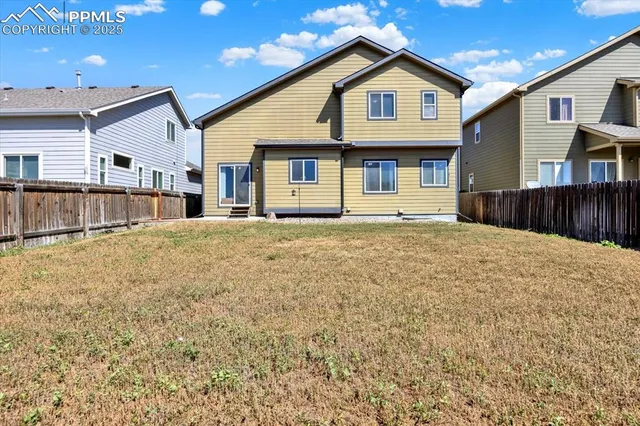 a front view of a house with a large tree and wooden fence