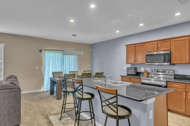 a kitchen with stainless steel appliances granite countertop table chairs sink and cabinets