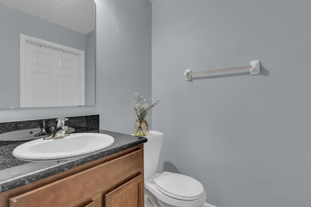 a bathroom with a granite countertop sink toilet and a mirror