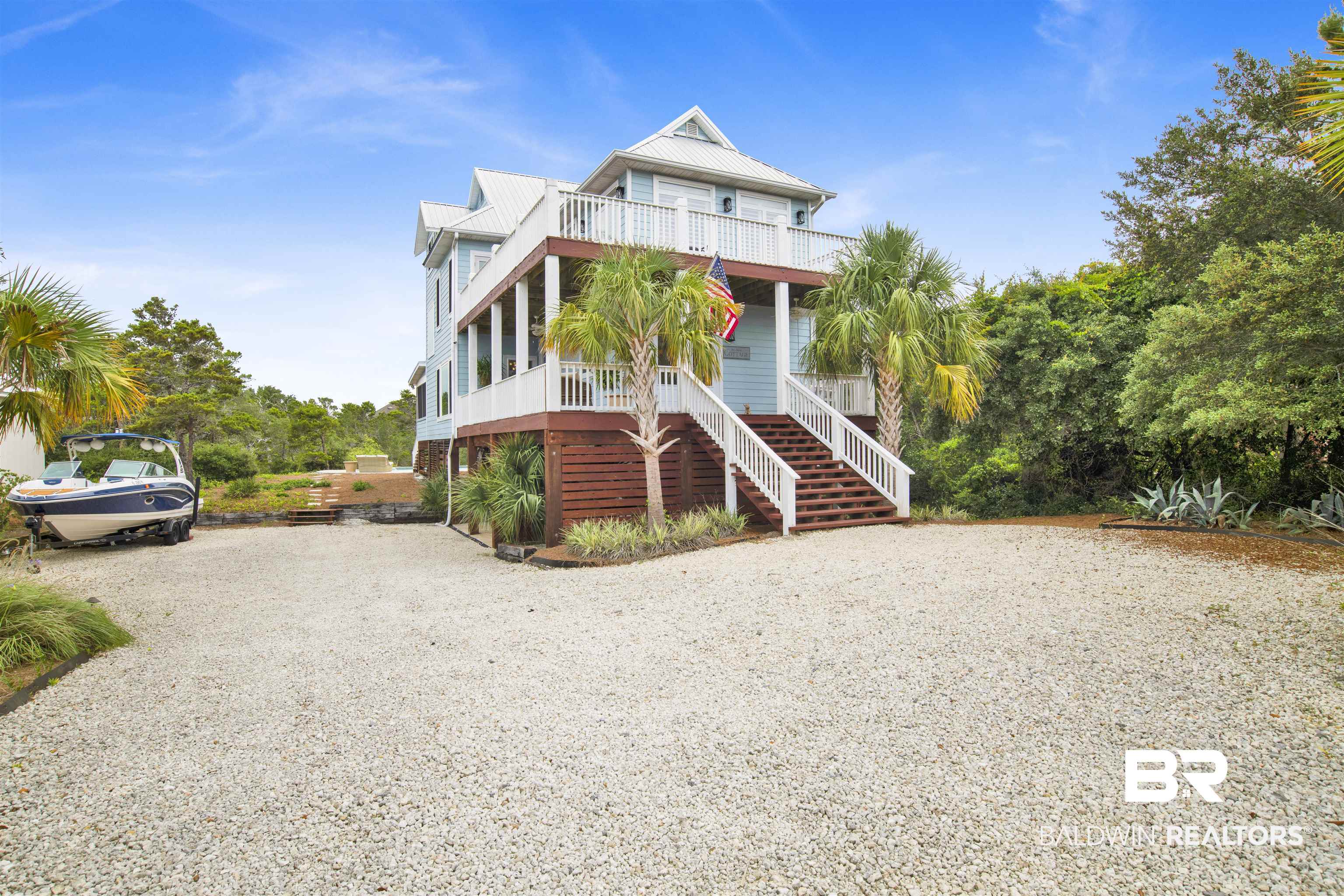 30351 River Road Orange Beach, AL 36561 - Photo 33 of 44 Elevated coastal residence featuring multiple balconies, a metal roof, and a spacious gravel driveway