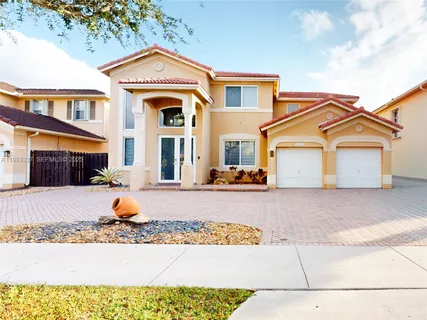 a view of a white house with large windows and a tree
