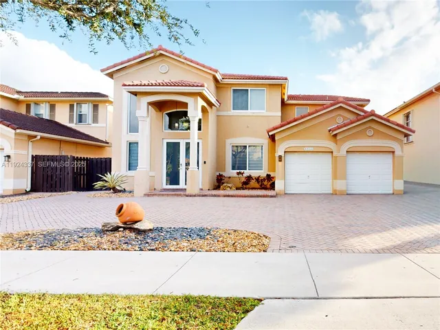 a view of a white house with large windows and a tree