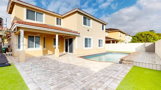 a view of a white house with swimming pool and wooden fence