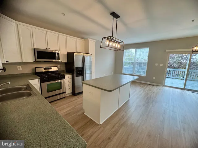 a kitchen with stainless steel appliances granite countertop a stove top oven a refrigerator a sink and a wooden floors