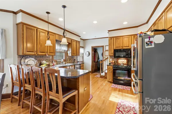 a kitchen with stainless steel appliances kitchen island granite countertop a refrigerator a stove top oven and a sink with granite countertops