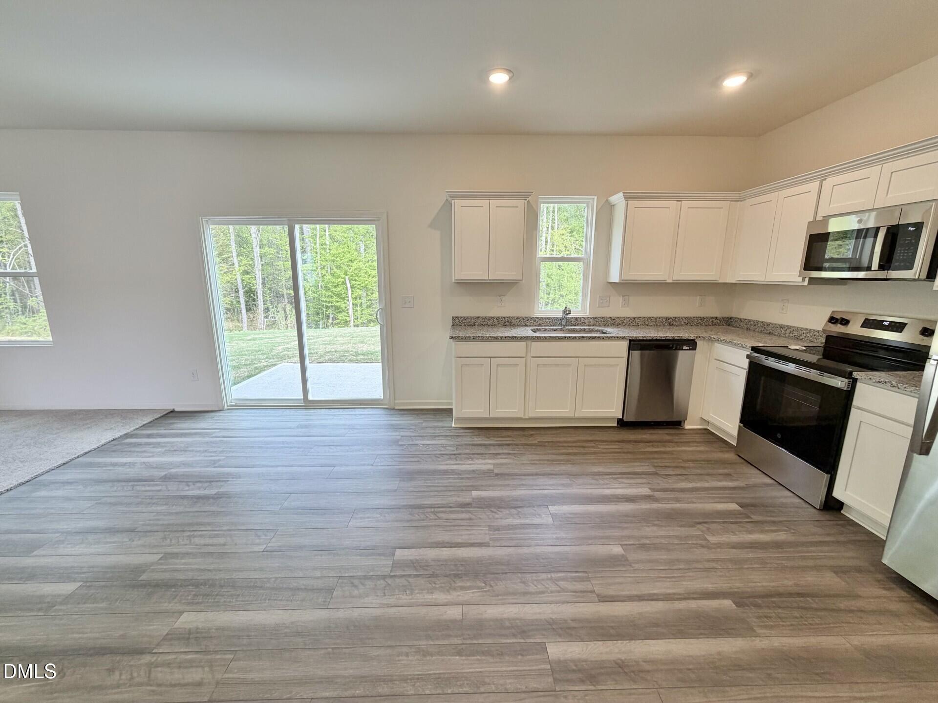 1010 Bombardier Alley Spring Hope, NC 27882 - Photo 9 of 30 a large kitchen with granite countertop a stove top oven a sink dishwasher a dining table and chairs with wooden floor