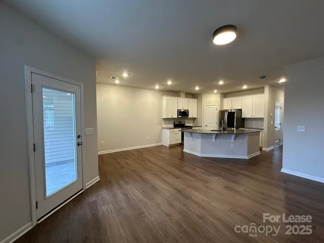 a view of kitchen with kitchen island wooden floor and refrigerator