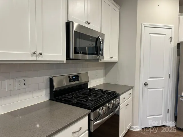 a kitchen with stainless steel appliances granite countertop white cabinets and a stove