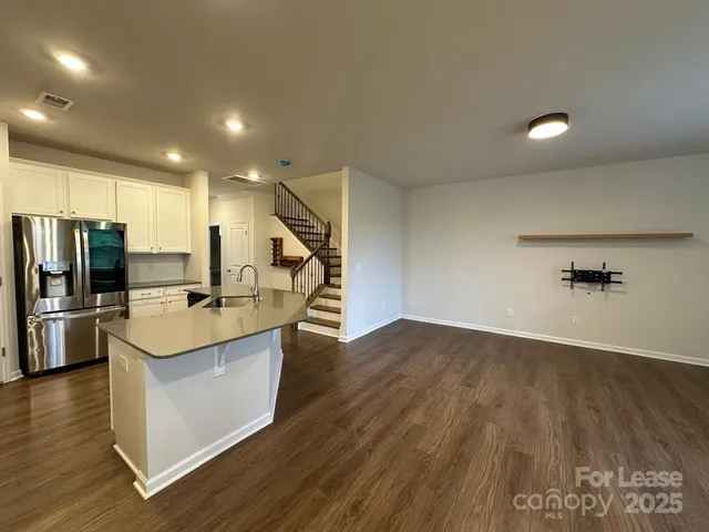 a view of a kitchen with kitchen island a sink wooden floor and stainless steel appliances
