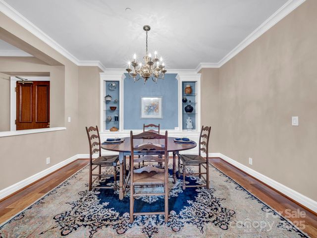 a dining room with wooden floor a chandelier a wooden table and chairs