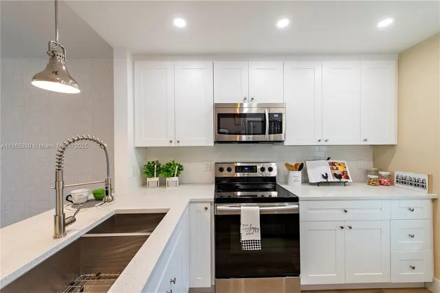 a kitchen with white cabinets stainless steel appliances and a counter space
