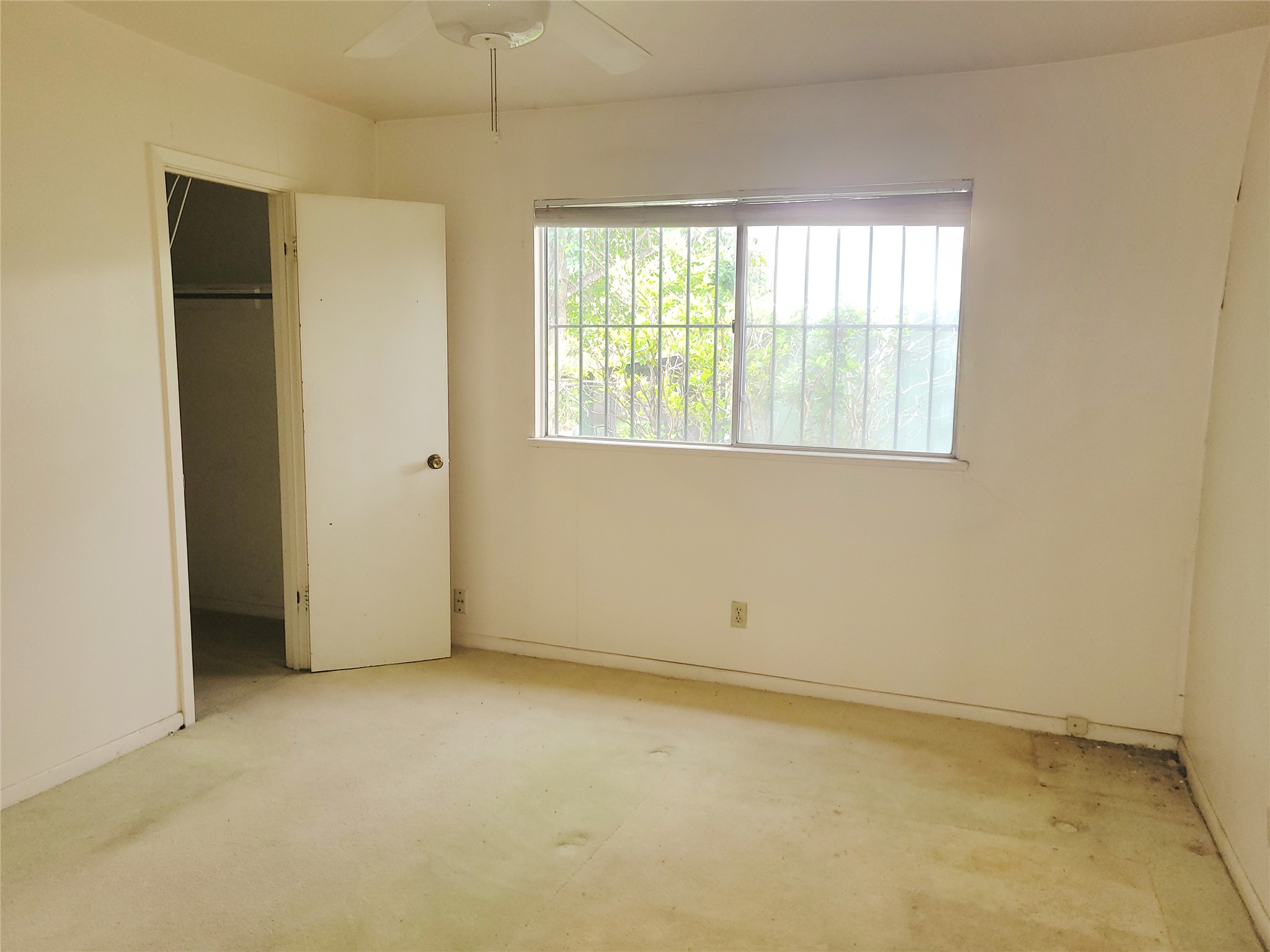 6605 Highpoint Drive Austin, TX 78723 - Photo 11 of 11 Interior room featuring a window with security bars, a ceiling fan, and a built-in closet with an open doorway