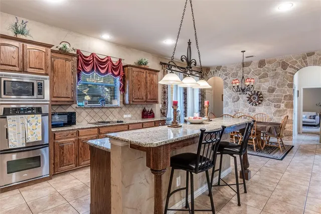 a kitchen with stainless steel appliances granite countertop table chairs sink and cabinets