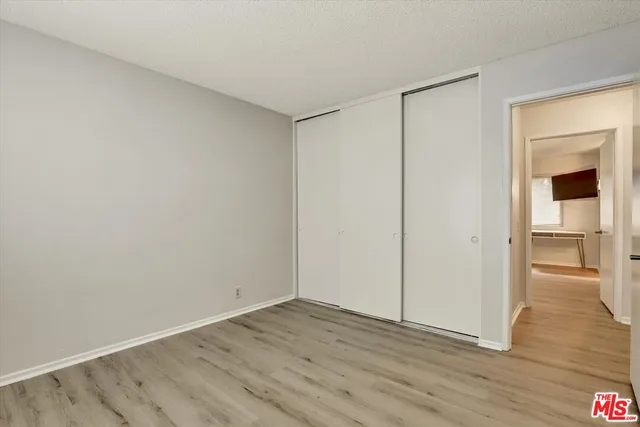 a view of an empty room with wooden floor and closet
