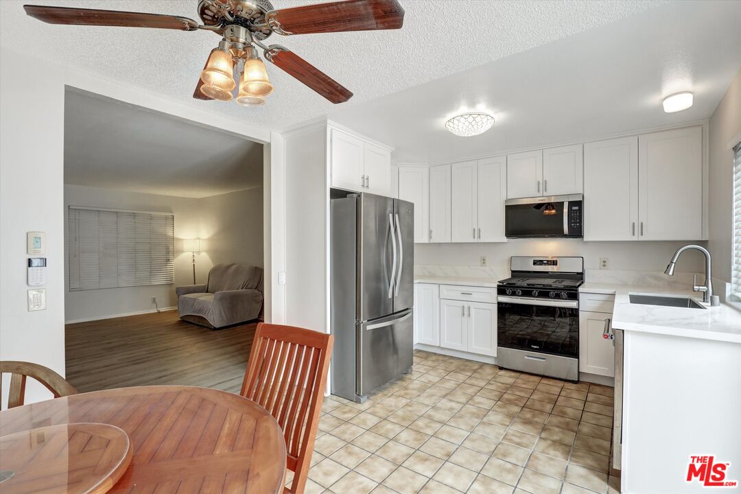 82 Eagle Point, Unit 43 Irvine, CA 92604 - Photo 6 of 35 a kitchen with stainless steel appliances granite countertop a refrigerator a stove a sink a dining table and chairs with wooden floor