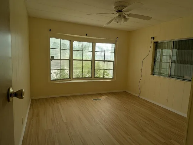 a view of an empty room with a window and wooden floor