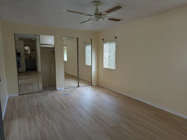 an empty room with wooden floor and a ceiling fan