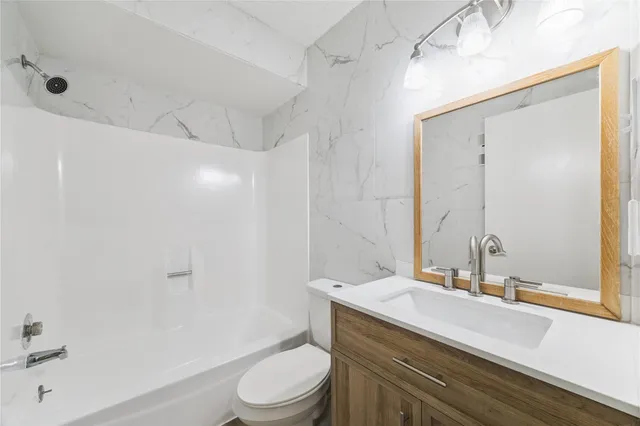 a bathroom with a granite countertop sink a toilet and shower