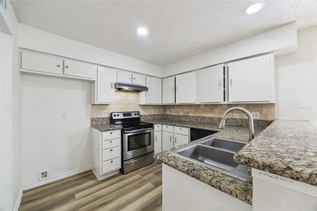 a kitchen with granite countertop a stove sink and cabinets