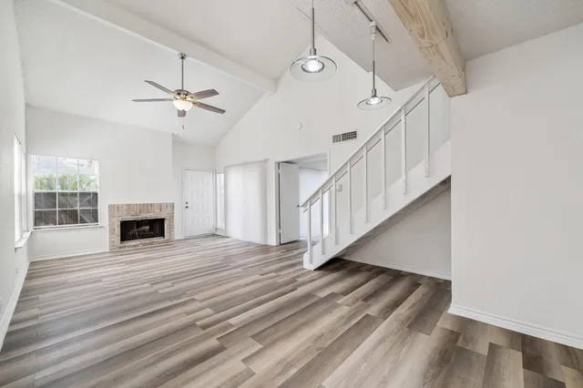 a view of an empty room with wooden floor fireplace and a window