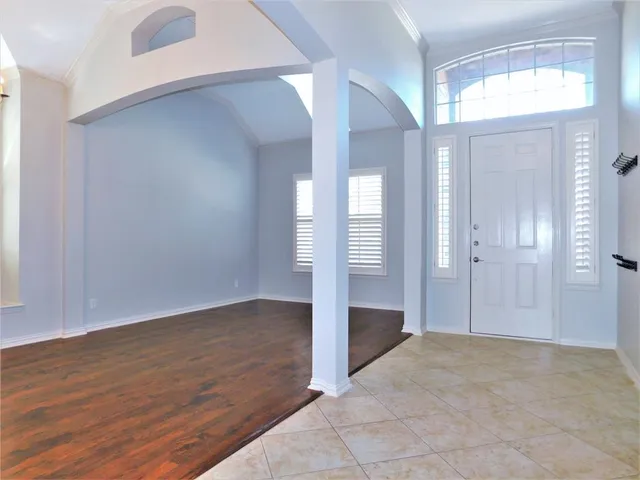 an empty room with wooden floor mirror and windows