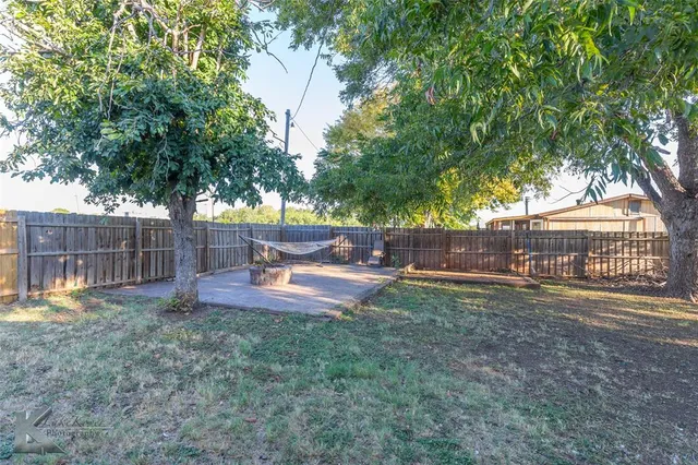 a view of backyard with large tree and wooden fence