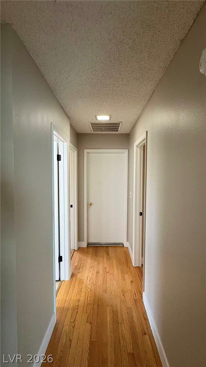 4325 Newcastle Road Las Vegas, NV 89103 - Photo 10 of 18 A well-lit hallway with natural hardwood flooring and multiple entryways invites exploration.