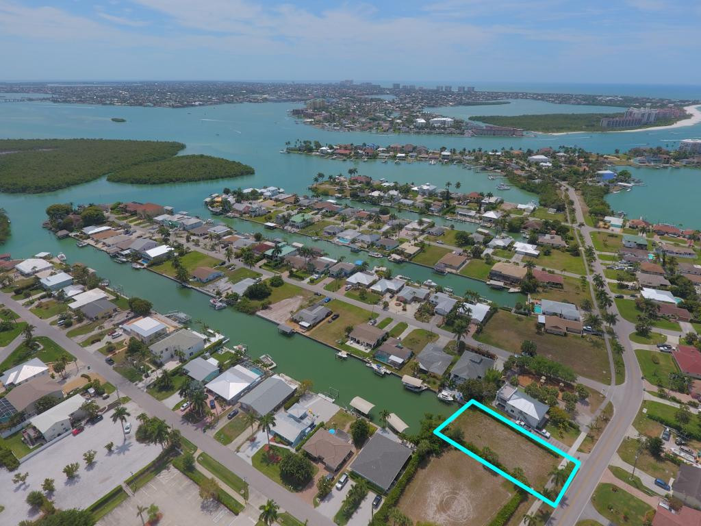 an aerial view of ocean and residential houses with outdoor space