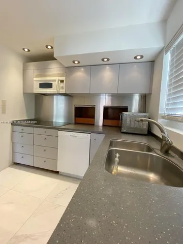 a kitchen with stainless steel appliances granite countertop a sink and a stove top oven with white cabinets