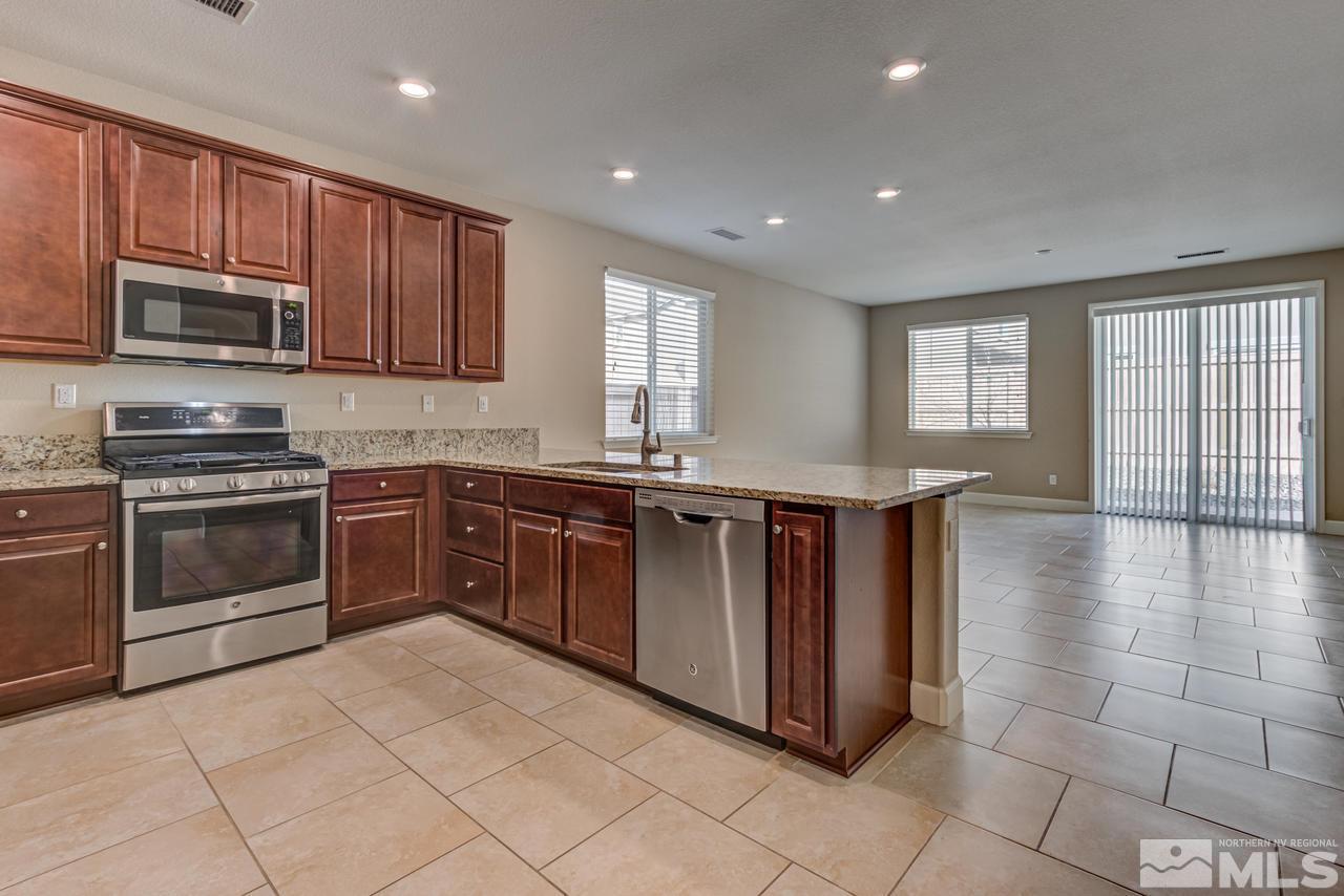 9728 Pachuca Drive Reno, NV 89521 - Photo 4 of 25 a kitchen with stainless steel appliances granite countertop a stove a sink and a microwave