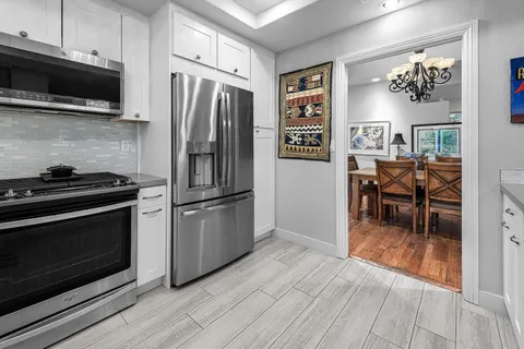 a kitchen with granite countertop a refrigerator stove and microwave with wooden floor