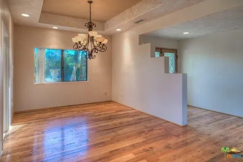 a view of a room with wooden floor chandelier and a window