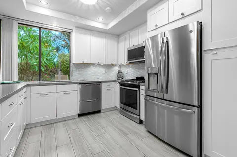 a kitchen with white cabinets stainless steel appliances and window
