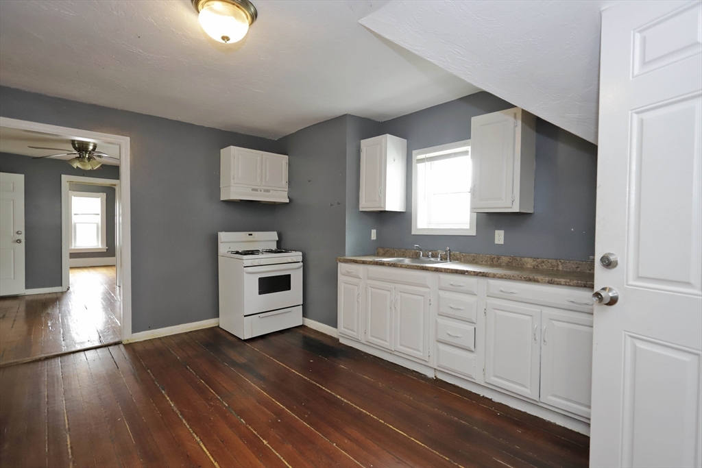 50-52 Rivet Street, Unit 2 New Bedford, MA 02744 - Photo 6 of 6 a kitchen with granite countertop a sink cabinets and wooden floor