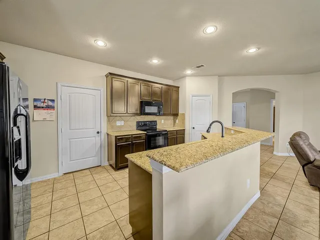 a kitchen that has a sink a refrigerator and a stove top oven