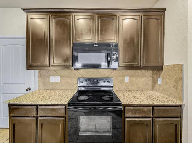 a kitchen with granite countertop a sink stove and cabinets
