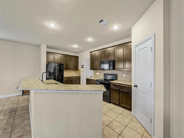 a kitchen with stainless steel appliances granite countertop a refrigerator sink stove oven and stove