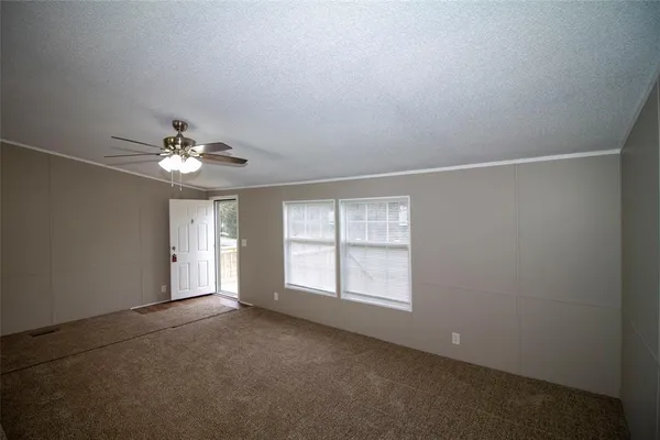 an empty room with chandelier fan and windows