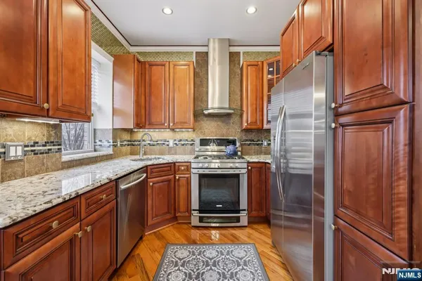 a kitchen with stainless steel appliances granite countertop a stove a sink a dining table and chairs with wooden floor