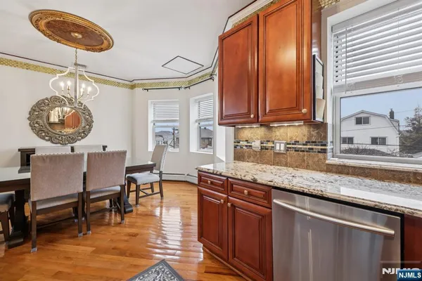 a kitchen with stainless steel appliances granite countertop a refrigerator a stove and a sink with wooden cabinets