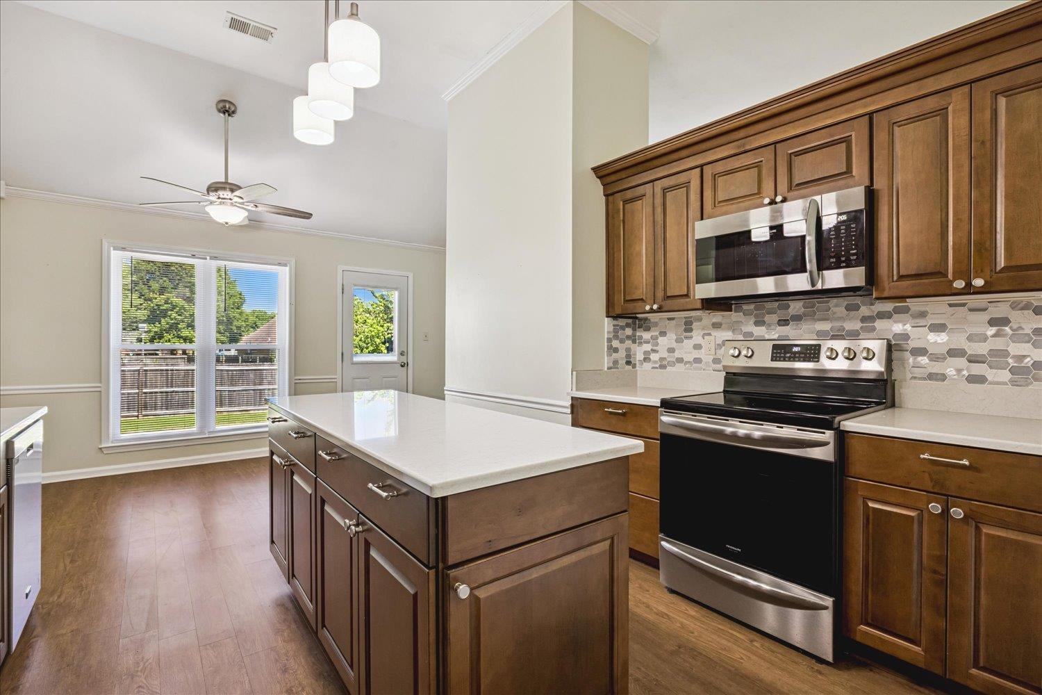 4654 Shadow Wick Lane Bartlett, TN 38002 - Photo 13 of 26 Kitchen featuring a central island with white countertop, warm wood cabinetry with brushed nickel hardware, and stainless steel appliances including a range and microwave