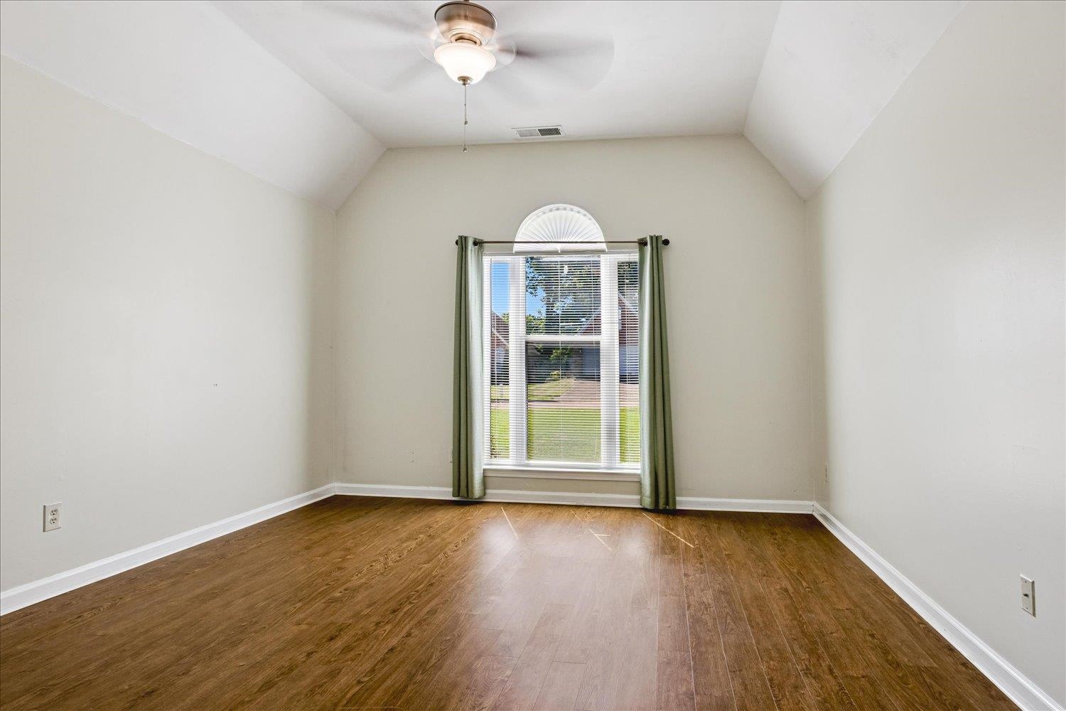 4654 Shadow Wick Lane Bartlett, TN 38002 - Photo 15 of 26 Bright interior space featuring a window with an arched transom, wood-finish flooring, vaulted ceiling, and a ceiling fan with integrated lighting