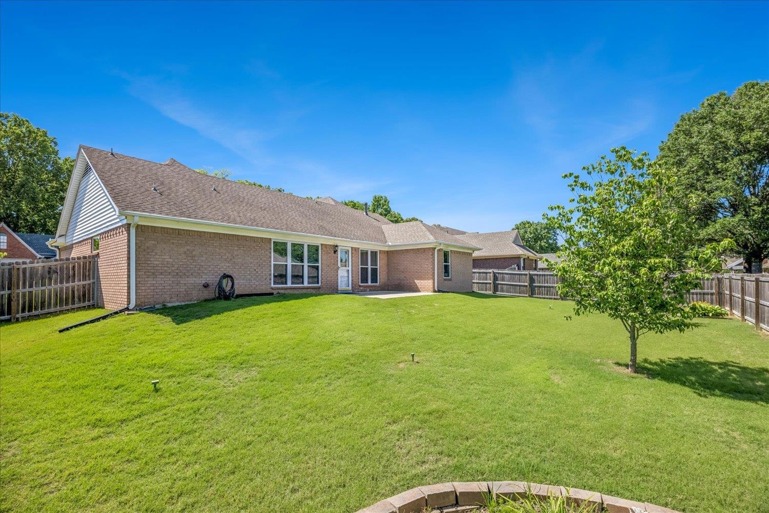 4654 Shadow Wick Lane Bartlett, TN 38002 - Photo 26 of 26 Expansive green lawn with a mature tree and a brick exterior dwelling featuring a composition shingle roof