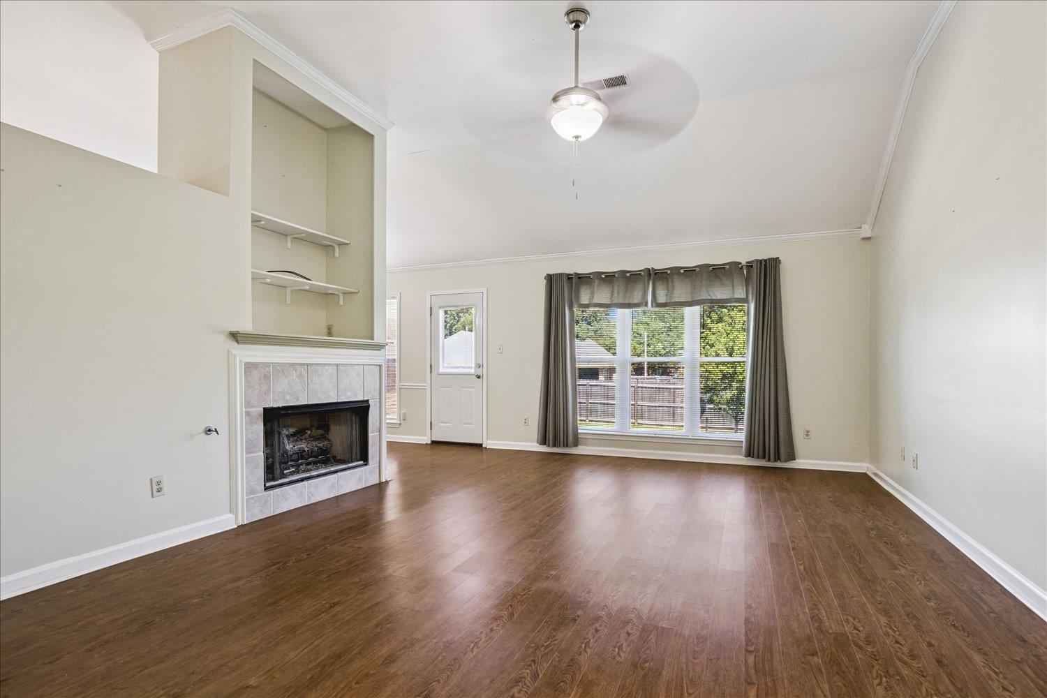 4654 Shadow Wick Lane Bartlett, TN 38002 - Photo 7 of 26 Living area featuring wood-finish flooring, a tiled fireplace with mantel, built-in shelving, vaulted ceiling, and a ceiling fan