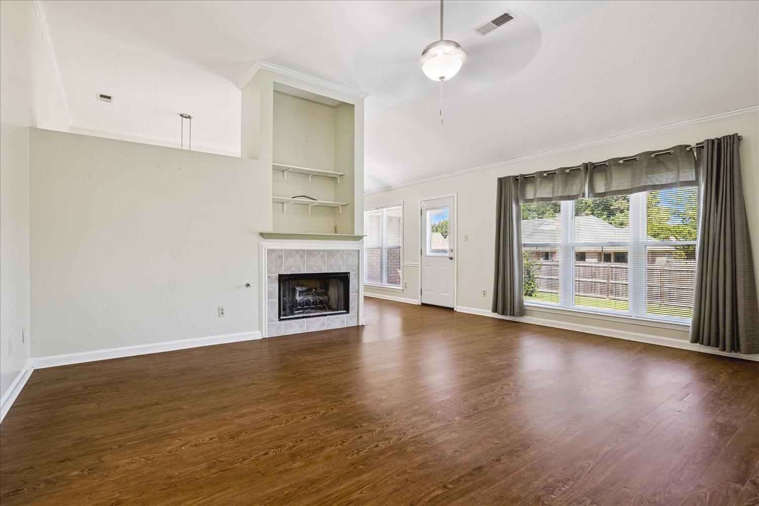 4654 Shadow Wick Lane Bartlett, TN 38002 - Photo 8 of 26 Spacious living area featuring wood-finish flooring, a tiled fireplace with mantel, built-in shelving, vaulted ceilings, and a ceiling fan