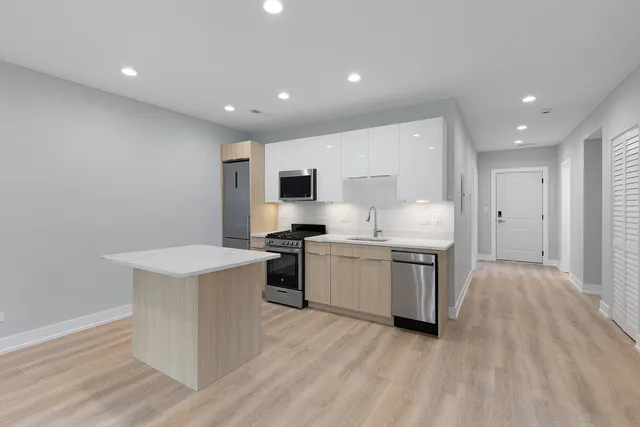 a kitchen with a sink white cabinets and stainless steel appliances