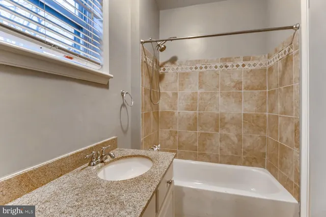 a bathroom with a granite countertop sink and a bathtub