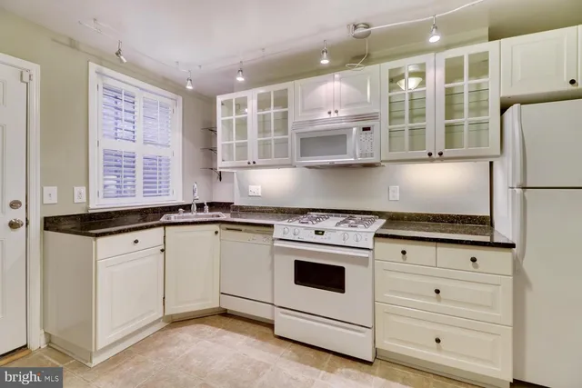 a kitchen with granite countertop white cabinets and white appliances