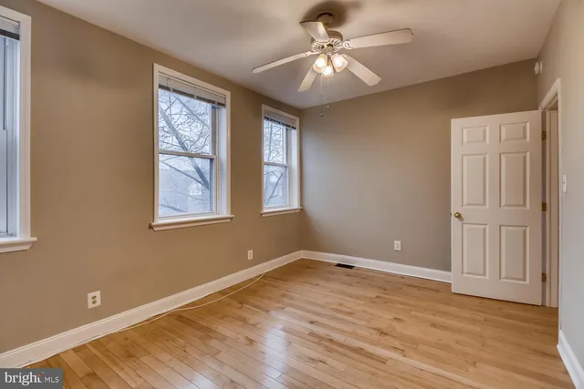 an empty room with wooden floor chandelier fan and windows