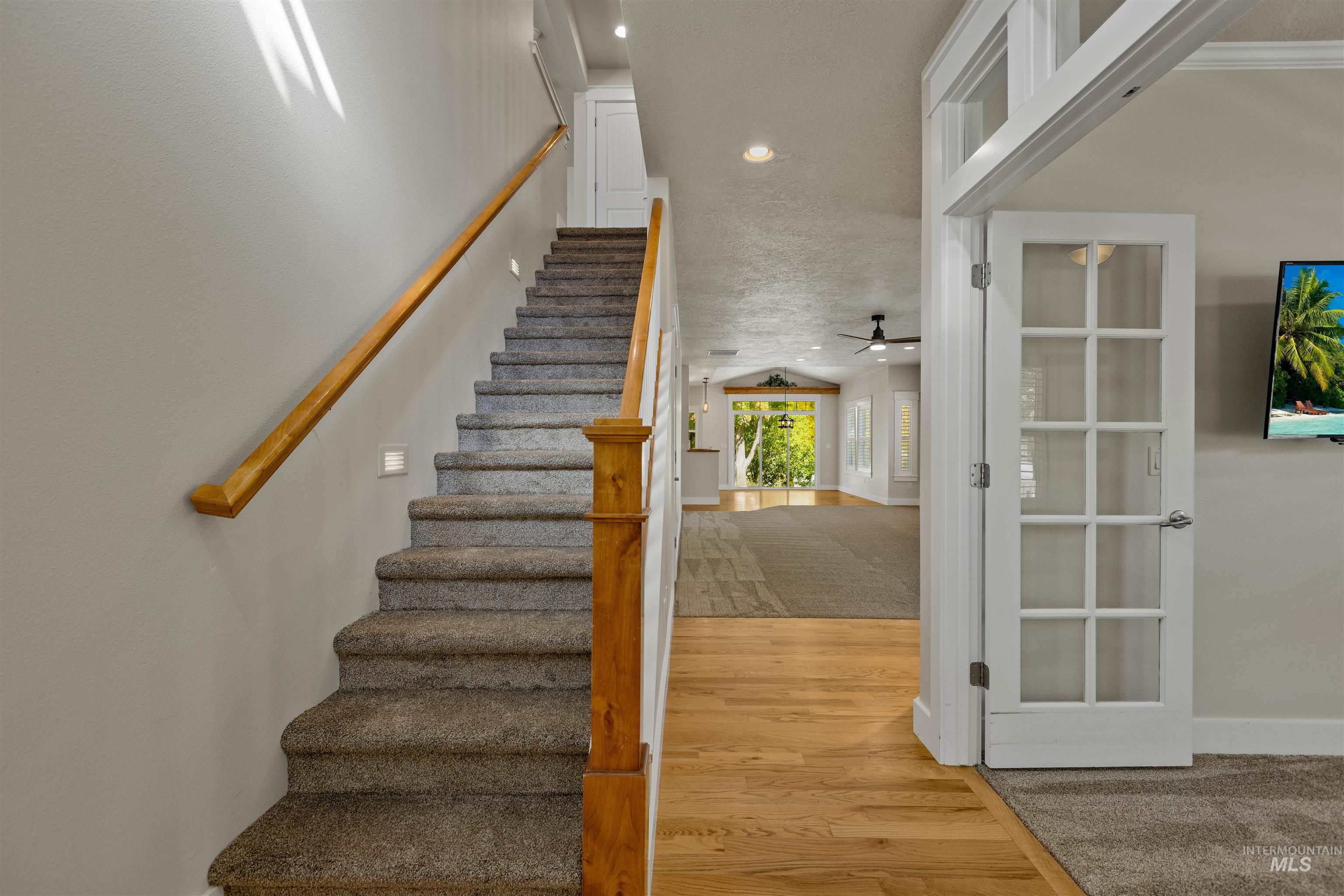 5426 West School Ridge Road Boise, ID 83714 - Photo 12 of 39 Wood-finish flooring, carpeted staircase with wood handrail, recessed lighting, and a white French door with transom window